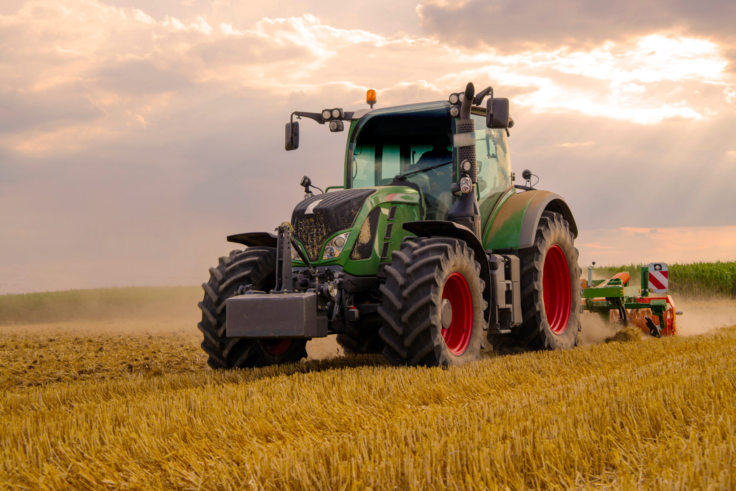 Green,Tractor,Plowing,Cereal,Field,With,Sky,With,Clouds